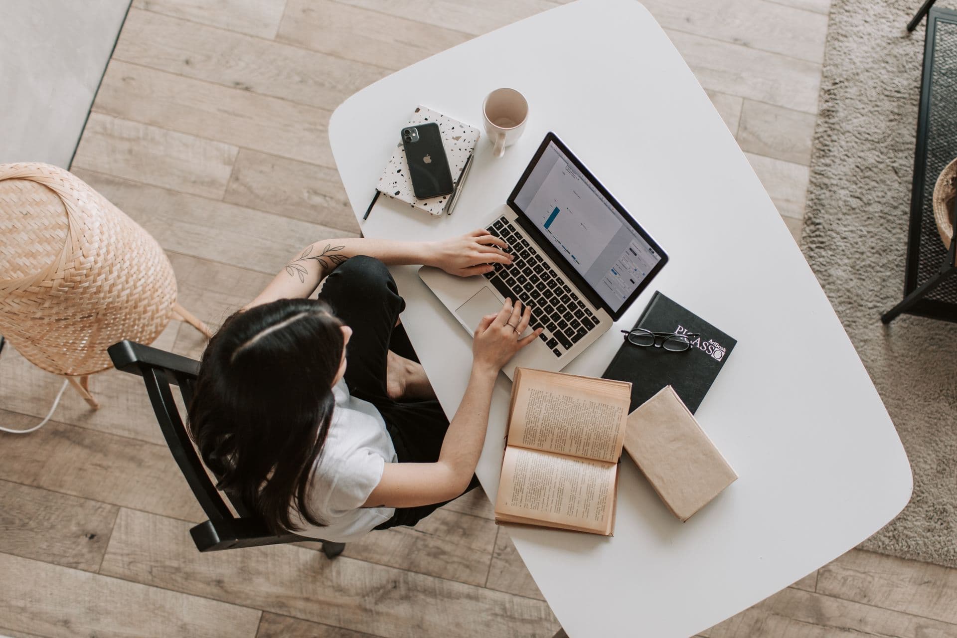 Uma pessoa trabalha no notebook ao lado de vários livros