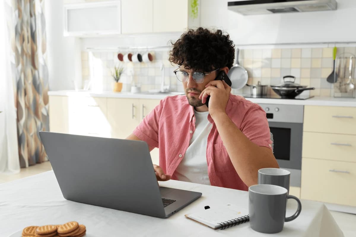 Ein Mann telefoniert bei der Arbeit am Laptop